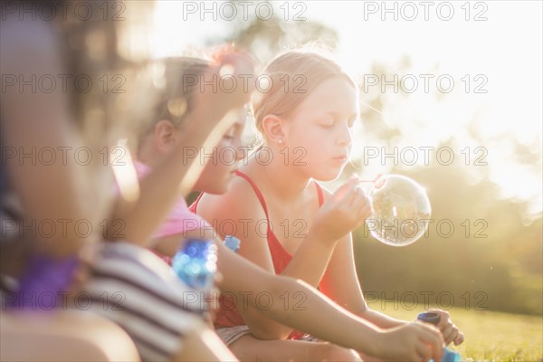Girls blowing bubbles in grass field