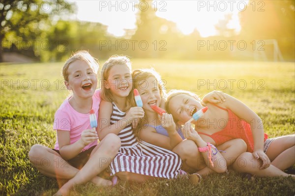 Girls eating flavored ice in sunny field