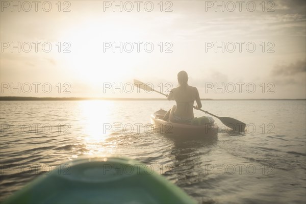 Caucasian woman rowing canoe on still lake