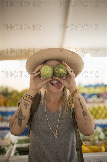 Caucasian woman making a face with fruit in farmers market