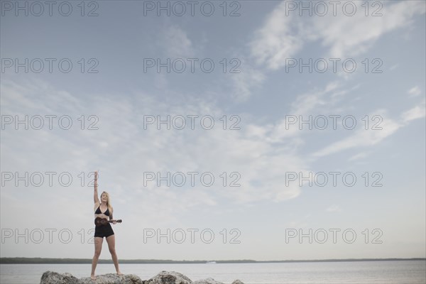 Caucasian woman playing ukulele by remote lake