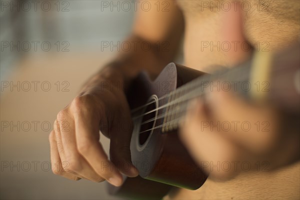Mixed race man playing ukulele on beach