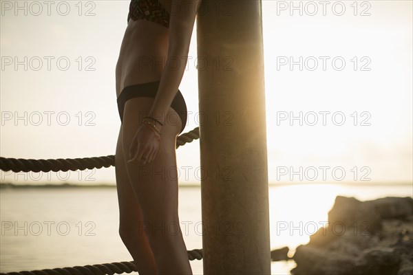 Caucasian woman standing by lake at sunset