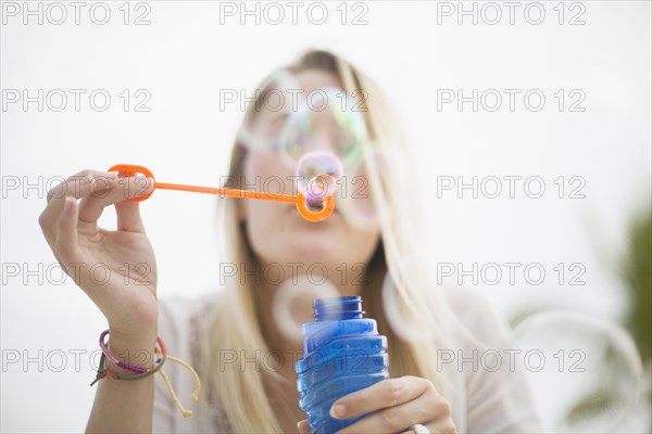 Caucasian woman blowing bubbles outdoors
