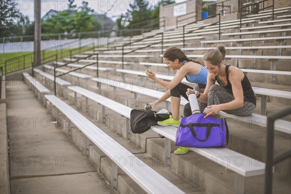 Women packing gym bags on bleachers