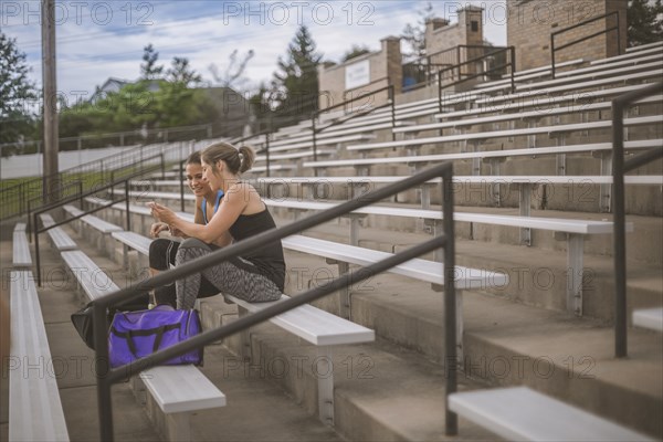 Women using cell phone on bleachers