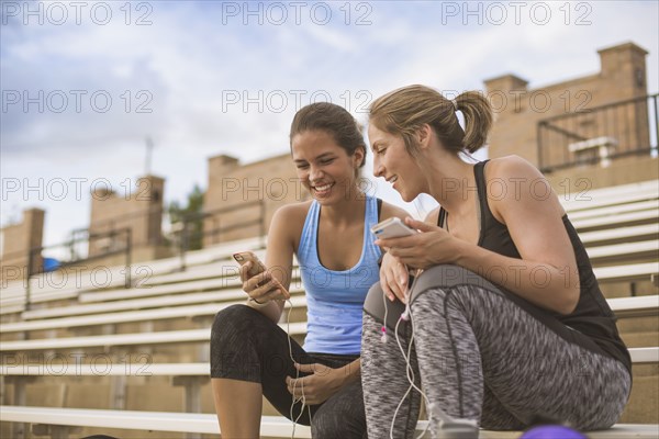 Women using cell phones on bleachers