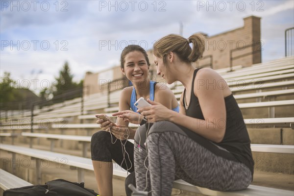 Women using cell phones on bleachers