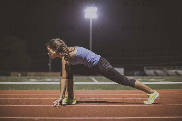 Mixed race runner in starting position on sports field