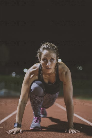 Caucasian runner in starting position on sports field