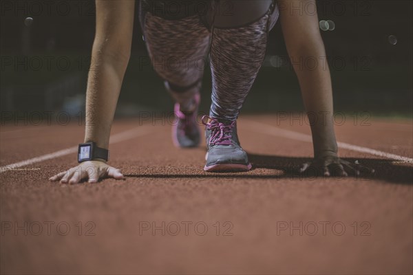 Caucasian runner in starting position on sports field