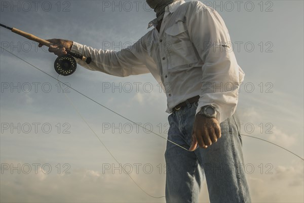 Close up of Caucasian man fishing under blue sky