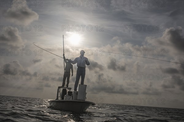 Caucasian fishermen casting lines on boat