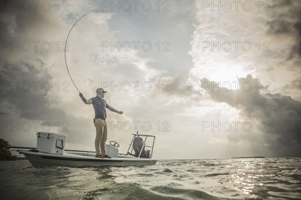 Caucasian fisherman casting line from boat