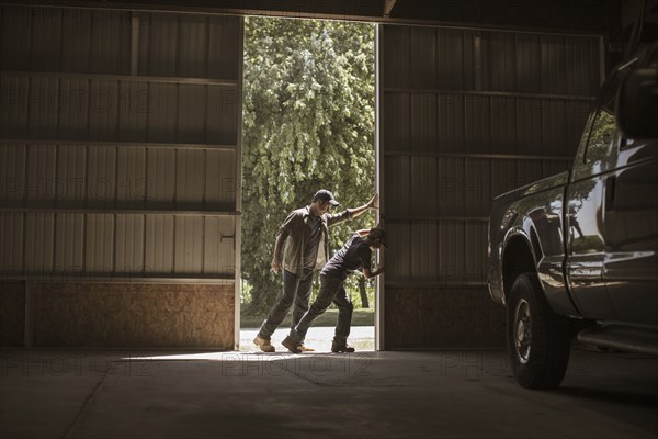 Caucasian father and son opening barn door