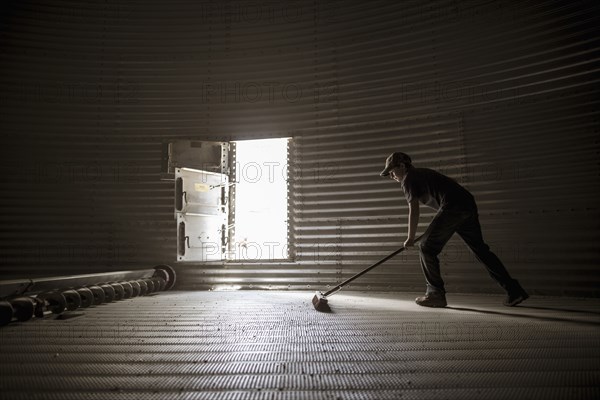 Caucasian boy sweeping empty silo