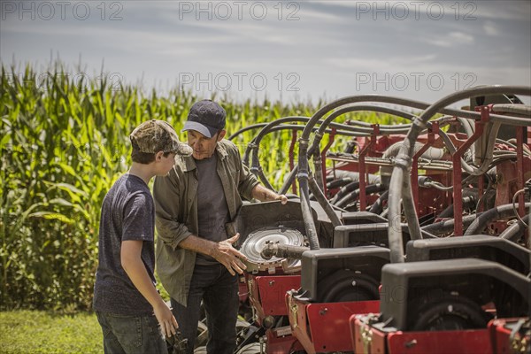 Caucasian farmer explaining machinery to son on farm