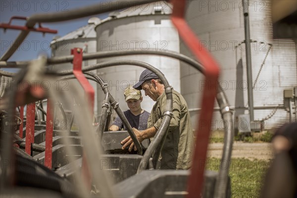 Caucasian farmer explaining machinery to son on farm