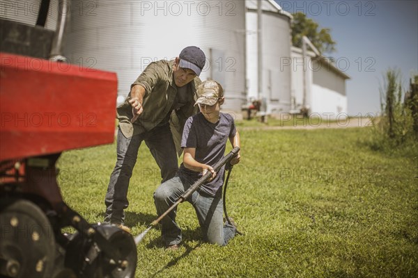 Caucasian farmer and son cleaning machinery on farm