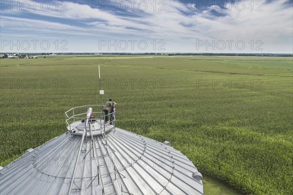 Caucasian farmer and son admiring farm from silo