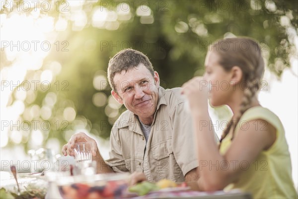 Caucasian father and daughter eating in backyard