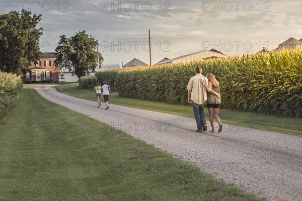 Caucasian family walking on dirt path by corn field