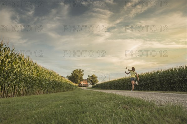 Caucasian girl walking on dirt path by corn field