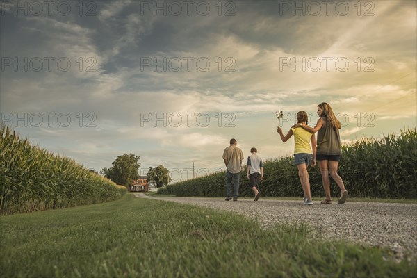 Caucasian family walking on dirt path by corn field