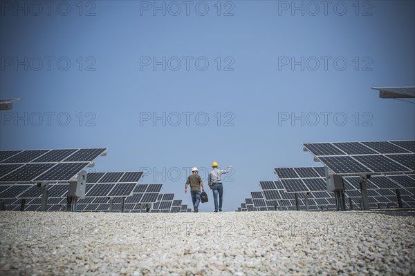 Caucasian technicians talking near solar panels