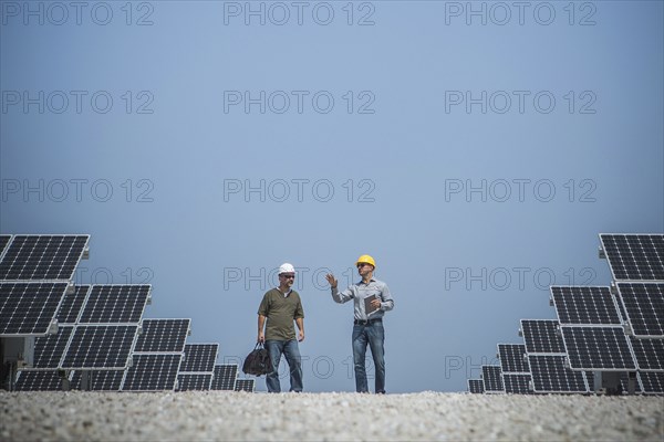 Caucasian technicians talking near solar panels