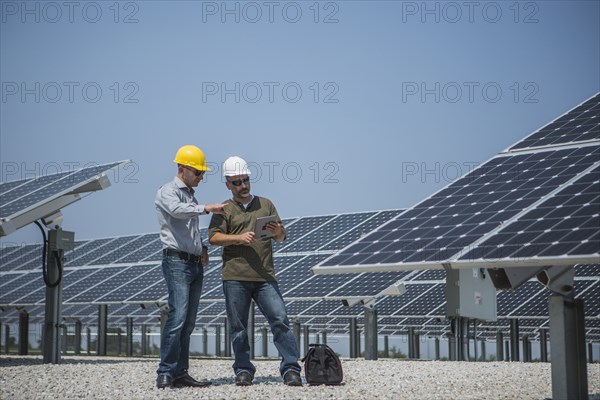 Caucasian technicians talking near solar panels