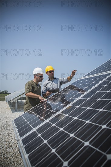 Caucasian technicians examining solar panels