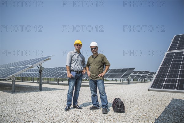 Caucasian technicians standing near solar panels