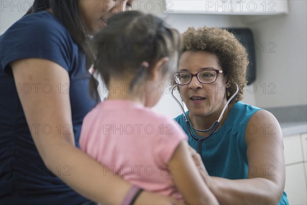 Doctor listening to chest of girl