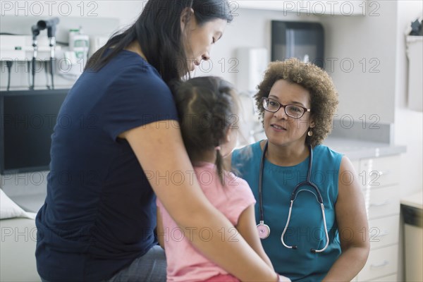 Doctor talking to mother and daughter in hotel room