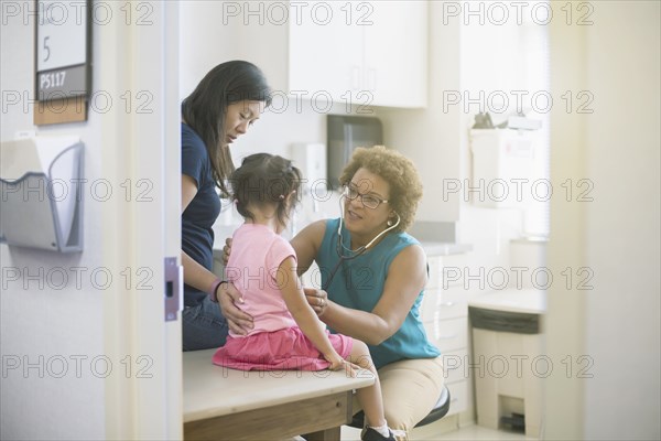 Doctor listening to chest of girl in hospital room