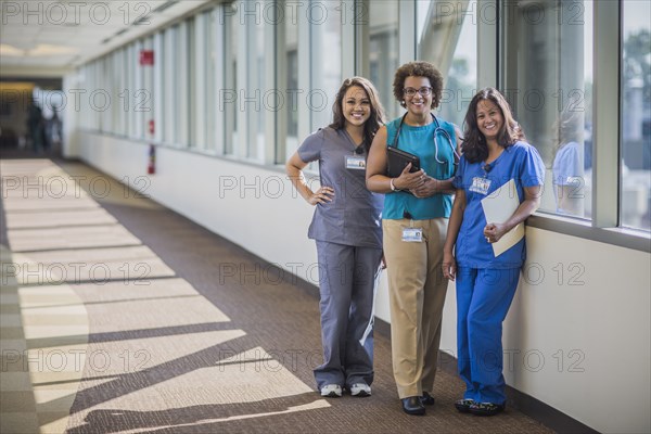 Nurses and doctor smiling in hospital hallway