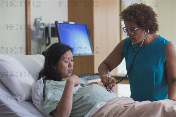 Doctor listening to belly of pregnant patient