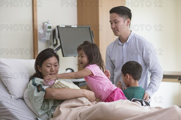 Family admiring newborn baby in hospital room