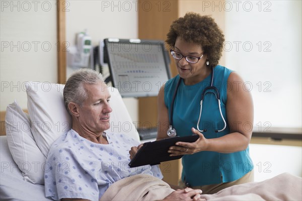 Doctor using digital tablet with patient in hotel room