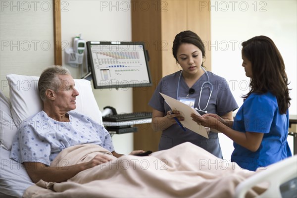 Nurses and patient talking in hospital room