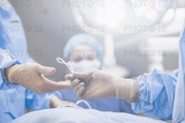 Surgeons handing forceps in operating room