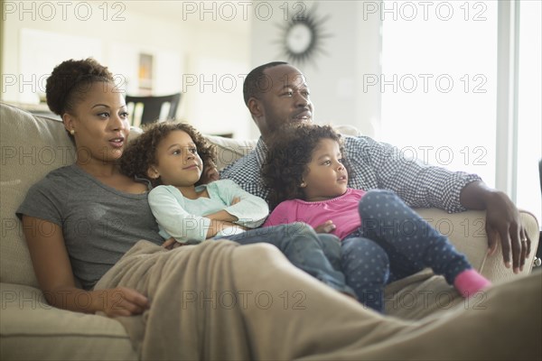 Family watching television on sofa