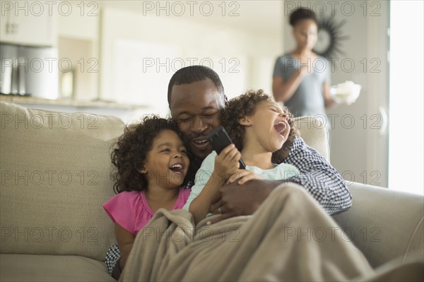 Father and daughters playing on sofa