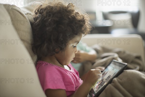 Girl using digital tablet on sofa