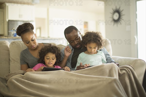 Family using digital tablets on sofa