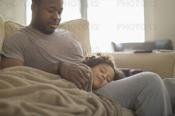 Father and daughter snuggling on sofa