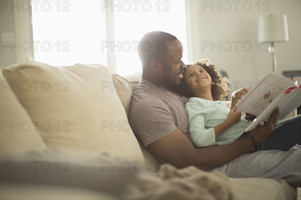 Father and daughter reading on sofa