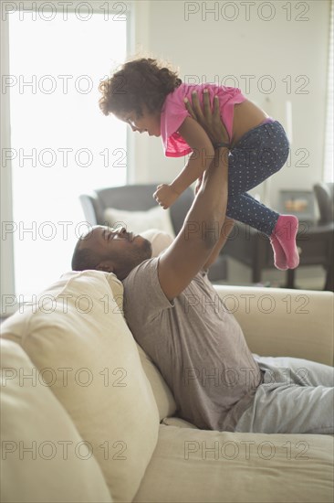 Father and daughter playing on sofa