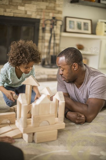 Father and daughter playing with building blocks in living room